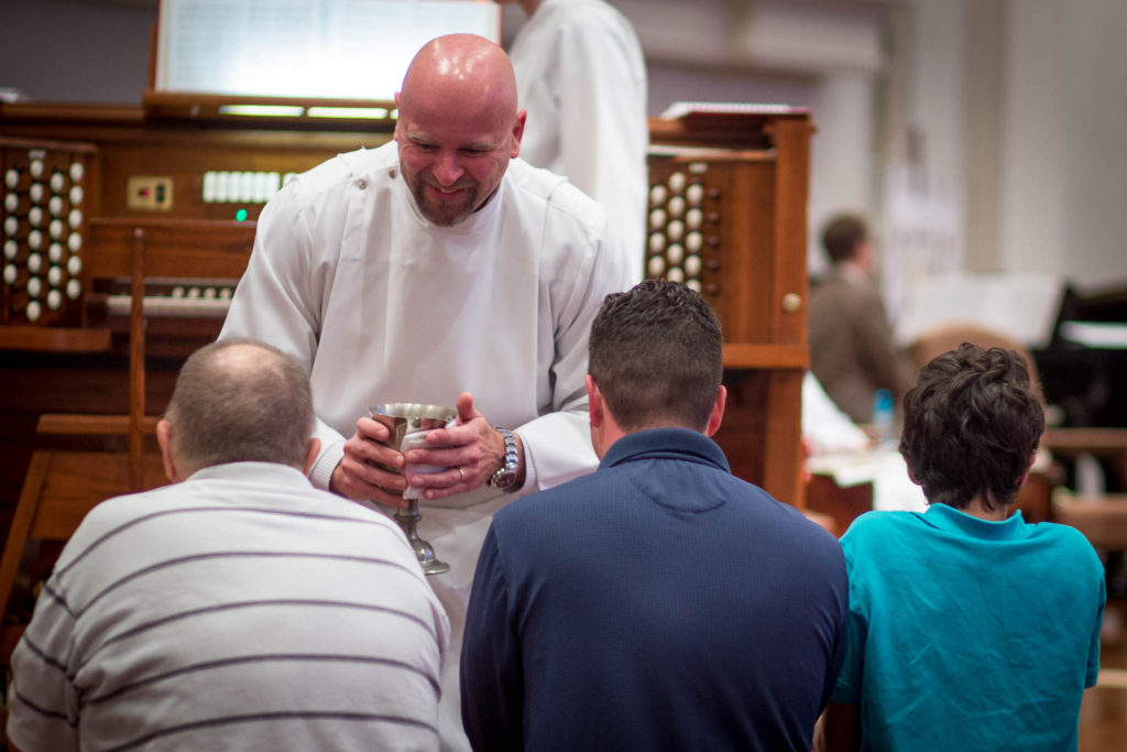 A worship assistant administers communion