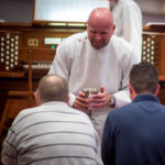 A worship assistant administers communion